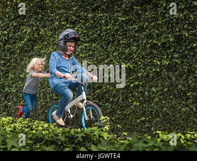 Nipote di nonna di spinta sulla sua bicicletta Foto Stock