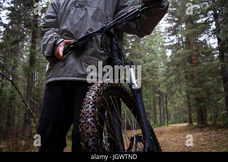 La sezione centrale dei maschi di mountain biker spingendo in mountain bike attraverso la foresta Foto Stock