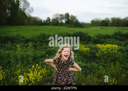 Ritratto di ragazza ondulata con capelli biondi ridendo nel campo Foto Stock