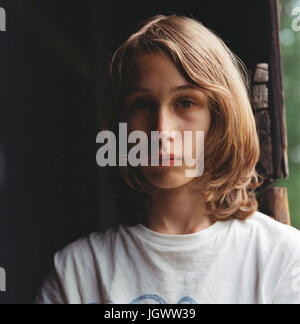 Ritratto di ragazzo con i capelli lunghi e pensieroso expression Foto Stock