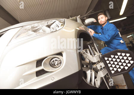 Fino ad oggi le tecnologie. Successo determinato esperto di auto che impiegano attrezzi speciali per fissare le ruote auto mentre si esegue una manutenzione in garage Foto Stock