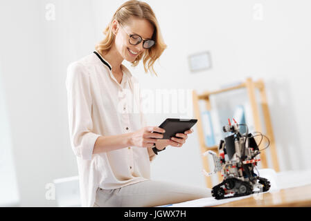 Sul mio modo di new tech scoperta . Professional smart allegro ingegnere di lavoro in laboratorio e utilizzo di tablet durante la collaborazione con l'elettronica di rob Foto Stock