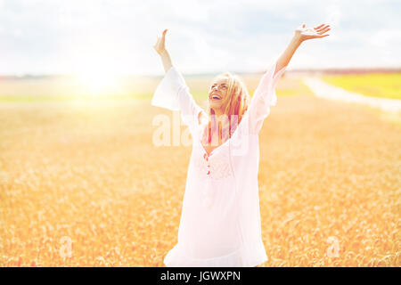 Sorridente giovane donna in abito bianco sul campo di cereali Foto Stock