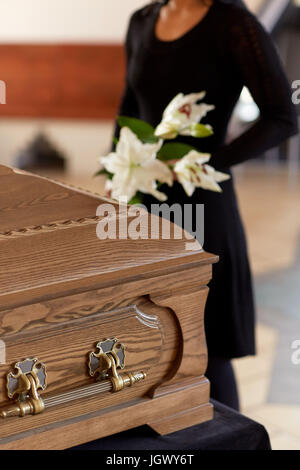 Donna con fiori e bara al funerale Foto Stock