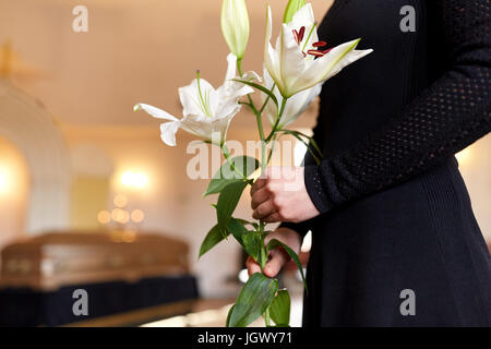 Close up di donna con giglio fiori ai funerali Foto Stock