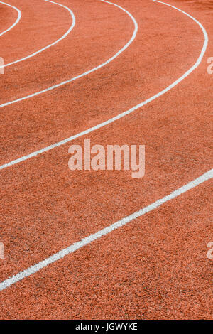 Vista ravvicinata di una pista atletica rossa con linee bianche che delimitano le corsie. Foto Stock