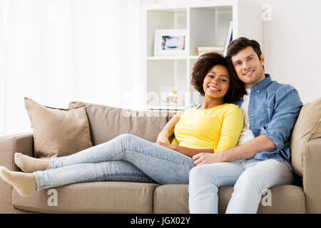 Sorridenti coppia internazionale sul divano di casa Foto Stock