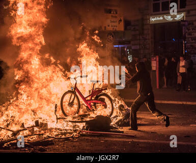 Amburgo, Germania. 7 Luglio, 2017. Un manifestante getta un pubblico city bike nella masterizzazione di Barricade. Manifestazioni violente contro il gruppo di 20 riunione al vertice ha portato a scontri tra polizia e manifestanti per la seconda notte consecutiva. Credito: Daniel Dohlus/ZUMA filo/Alamy Live News Foto Stock