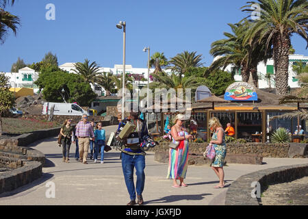 Afrikanischer strassenhaendler verkauft armbanduhren an der promenade beim badestrand playa de Las Cucharas, costa teguise, Lanzarote, kanarische inse Foto Stock