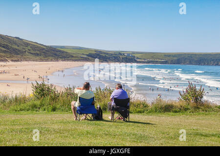 17 Giugno 2017: Woolacombe, North Devon, Inghilterra, Regno Unito - Giovane sit affacciato sulla spiaggia come persone godetevi il sole su uno dei giorni più caldi dell'y Foto Stock