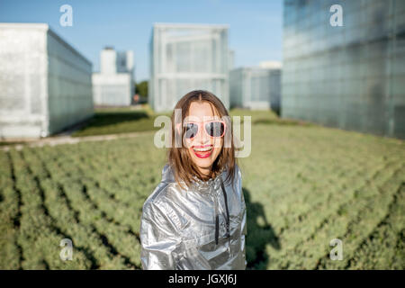 Donna in camicia argento presso la moderna serra con lattuga crescente Foto Stock