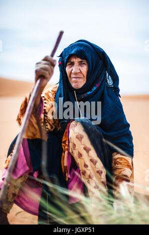 Ritratto di vecchio Berber donna seduta su di una duna di Merzouga, Marocco Foto Stock