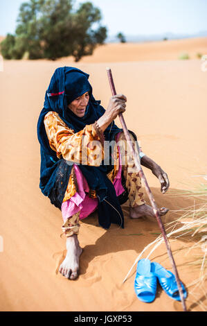 Ritratto di vecchio Berber donna seduta su di una duna di Merzouga, Marocco Foto Stock