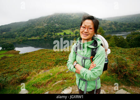 Sorridente East Asian Woman Hiking nel Lake District, Cumbria, Regno Unito. Foto Stock