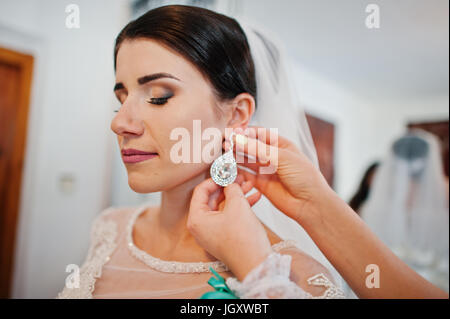 Damigella sposa aiuta a mettere su il suo matrimonio lussuoso orecchini. Foto Stock