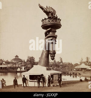 La torcia e la parte del braccio della Statua della Libertà, sul display a 1876 Centennial esposizione di Filadelfia. Informazioni stand alla base del braccio e due persone visto a ringhiera di protezione al di sotto di fiamma della torcia. Foto Stock