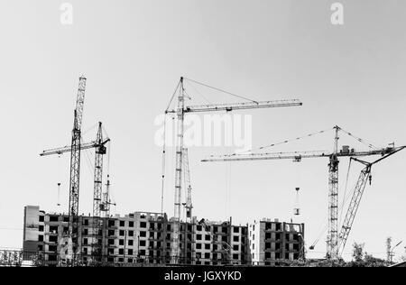 Un sacco di gru edili Costruzione edificio alto. Bianco nero foto retrò. Foto Stock