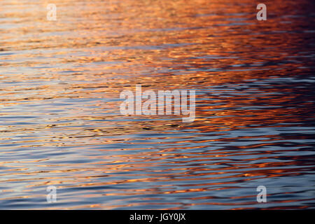 Bel rosso e arancione tramonto riflessioni su una tranquilla baia di acqua. Foto Stock