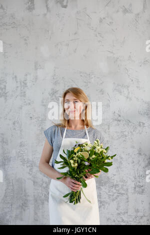 Foto di un fioraio con bouquet vicino al muro grigio Foto Stock