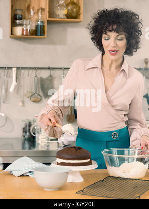 Donna decorare la torta al cioccolato con panna Foto Stock