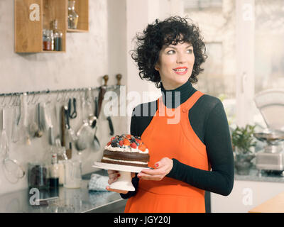 Donna che mantiene una torta al cioccolato decorata con fresca frutta estiva Foto Stock
