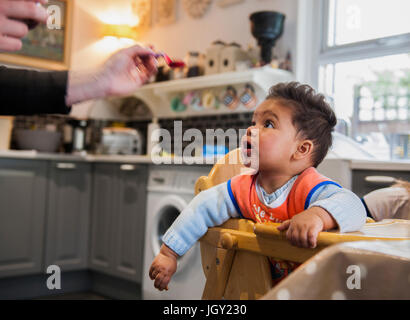 Baby boy nel seggiolone essendo alimentato Foto Stock