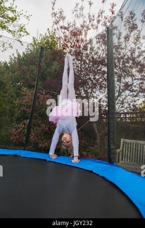 Ragazza sul trampolino indossando tutu facendo handstand Foto Stock