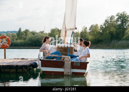 Tre amici rilassante sulla barca a vela sul lago