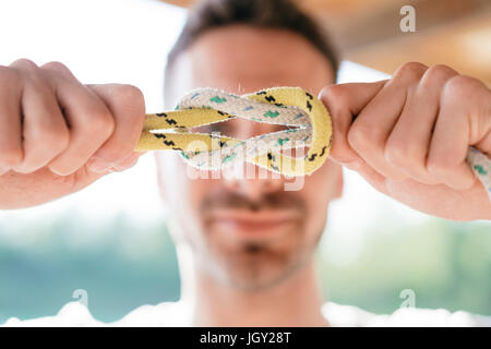 Uomo con la fune nella parte anteriore del volto, che mostra nodo nautico Foto Stock