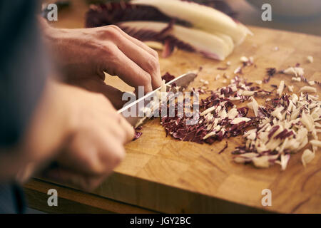 Vista ritagliata della chef per affettare le foglie di insalata Foto Stock