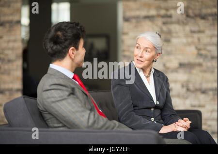 Imprenditrice e uomo avente incontro sul divano per ufficio Foto Stock
