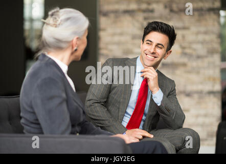Imprenditore e la donna avente incontro sul divano per ufficio Foto Stock