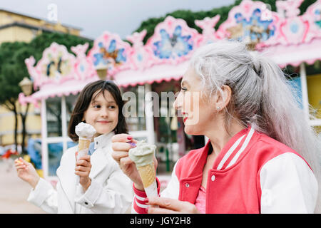 Donna matura e una ragazza a mangiare il gelato coni al di fuori di gelateria, Firenze, Italia Foto Stock