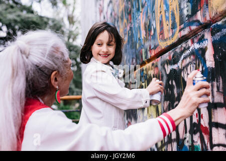 Donna matura e ragazza di verniciatura a spruzzo parete graffiti insieme Foto Stock