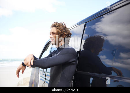 Kite surfer in wetsuit appoggiata contro auto, Hornbaek, Hovedstaden, Danimarca Foto Stock