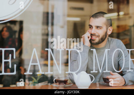 Giovane uomo seduto in cafe, vista attraverso la finestra Foto Stock