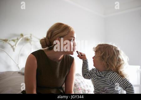 Figlia aiutando madre mise il rossetto Foto Stock