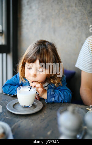 Ragazza sorseggiando il latte in cafe Foto Stock