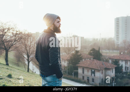 Giovane maschio hipster affacciato sul paesaggio urbano Foto Stock