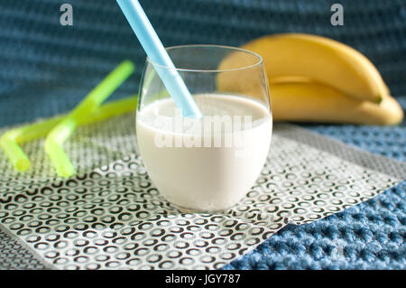 Cibo sano. Frullati di banana. Frullato e banane mature sul tessuto blu sullo sfondo a maglia Foto Stock