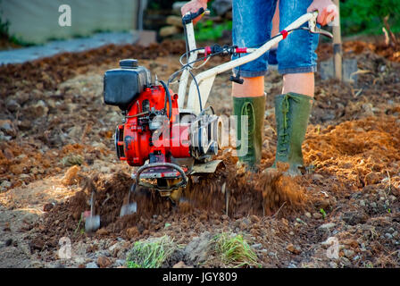 Contadino ara la terra con un coltivatore e prepararlo per la semina di verdure Foto Stock
