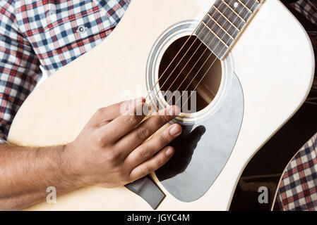 Close up vista parziale dell'Uomo in camicia suonare la chitarra acustica Foto Stock