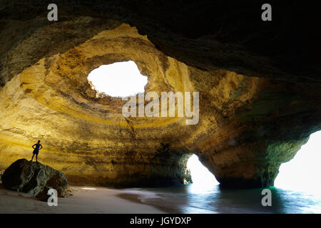 Silhouette di una donna in piedi sulla roccia in grotta a Benagil, Algarve, Portogallo. Foto Stock