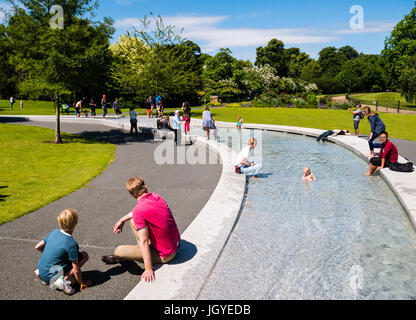 , UK, GBPeople godendo il sole, il Princess Diana Memorial Fountain, Hyde Park, Londra, Inghilterra, Regno Unito, GB. Foto Stock