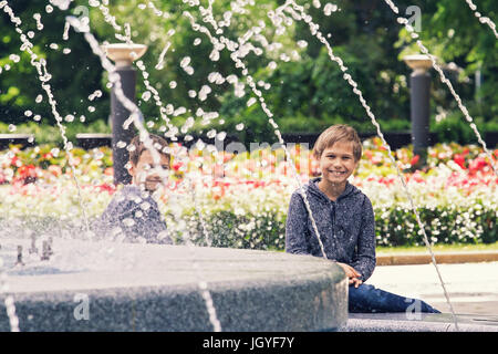 Contenti i bambini a giocare vicino alla fontana nel parco della città Foto Stock