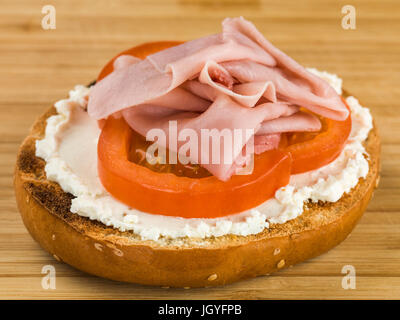 Pomodoro di prosciutto e formaggio di sesamo bagel su una cucina tagliere Foto Stock