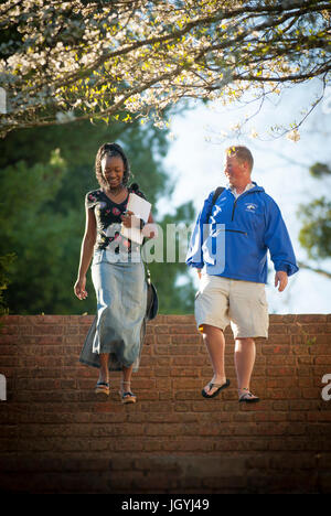 Studenti del College di parlare mentre passeggiando per le fasi di campus. Lei è americano africano, egli è caucasiche. Foto Stock