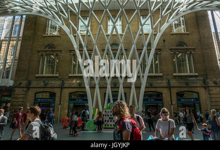 Persone in atrio principale alla stazione di King Cross a Londra, Inghilterra, Regno Unito, nella parte anteriore del gigante arcuata traliccio reticolare tetto di scultura da Arup Foto Stock