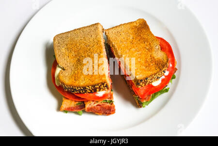 Un BLT su un piatto bianco con pancetta, lattuga, pomodoro e maionese sul pane tostato, un classico panino americano Foto Stock