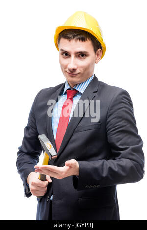 Un uomo in un vestito con un martello indossa un giallo casco di protezione Foto Stock